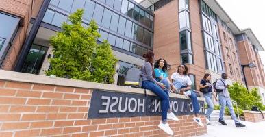 Students sitting and talking in front of Hugo Owens residence hall