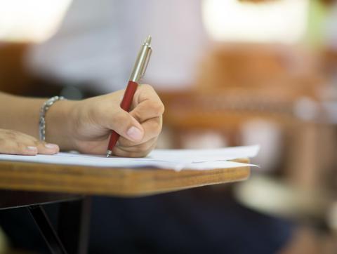 关闭up to hand of student holding pen and taking exam in cl